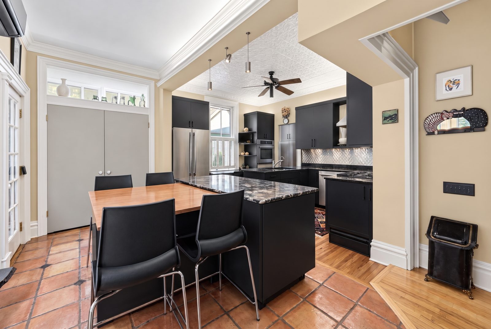 After: the same kitchen refinished in matte black with warm tan walls