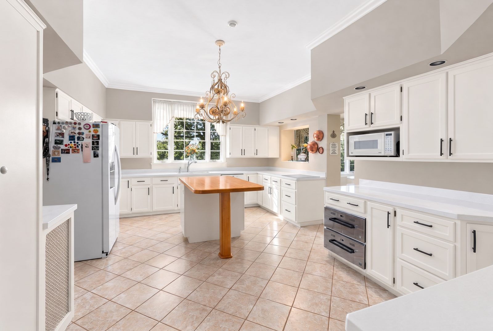 After: the same kitchen with crisp white cabinets, black hardware and clean greige walls